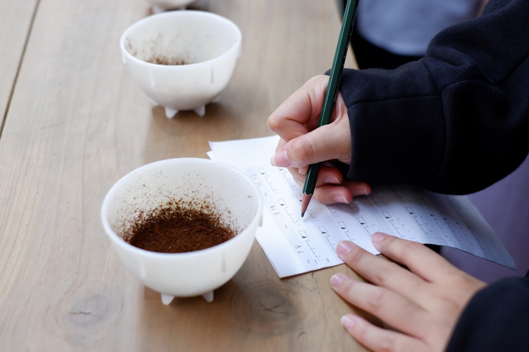A person writing on a piece of paper next to two cups of coffee